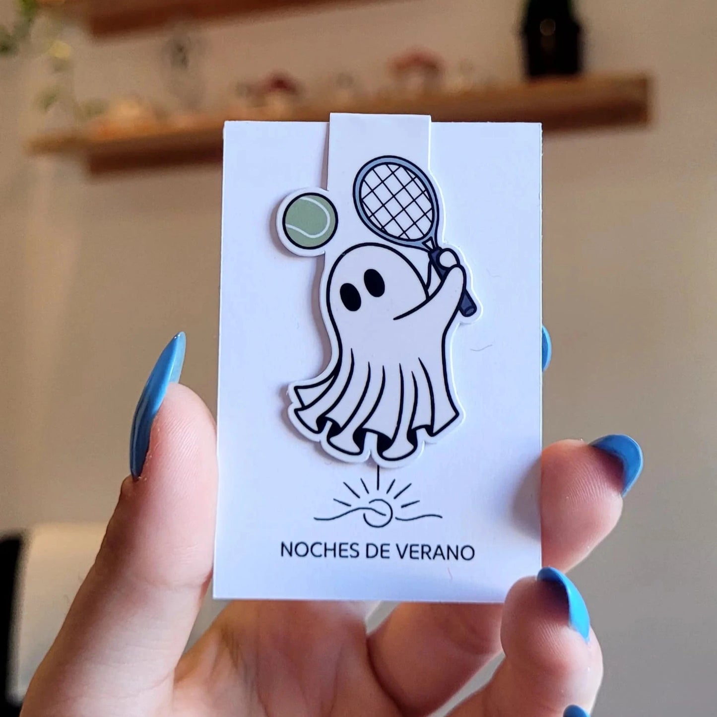 Marcapáginas magnético con diseño divertido de fantasma jugando al tenis con una raqueta, perfecto para lectores que busquen un marcador de libros único y original de deportes.