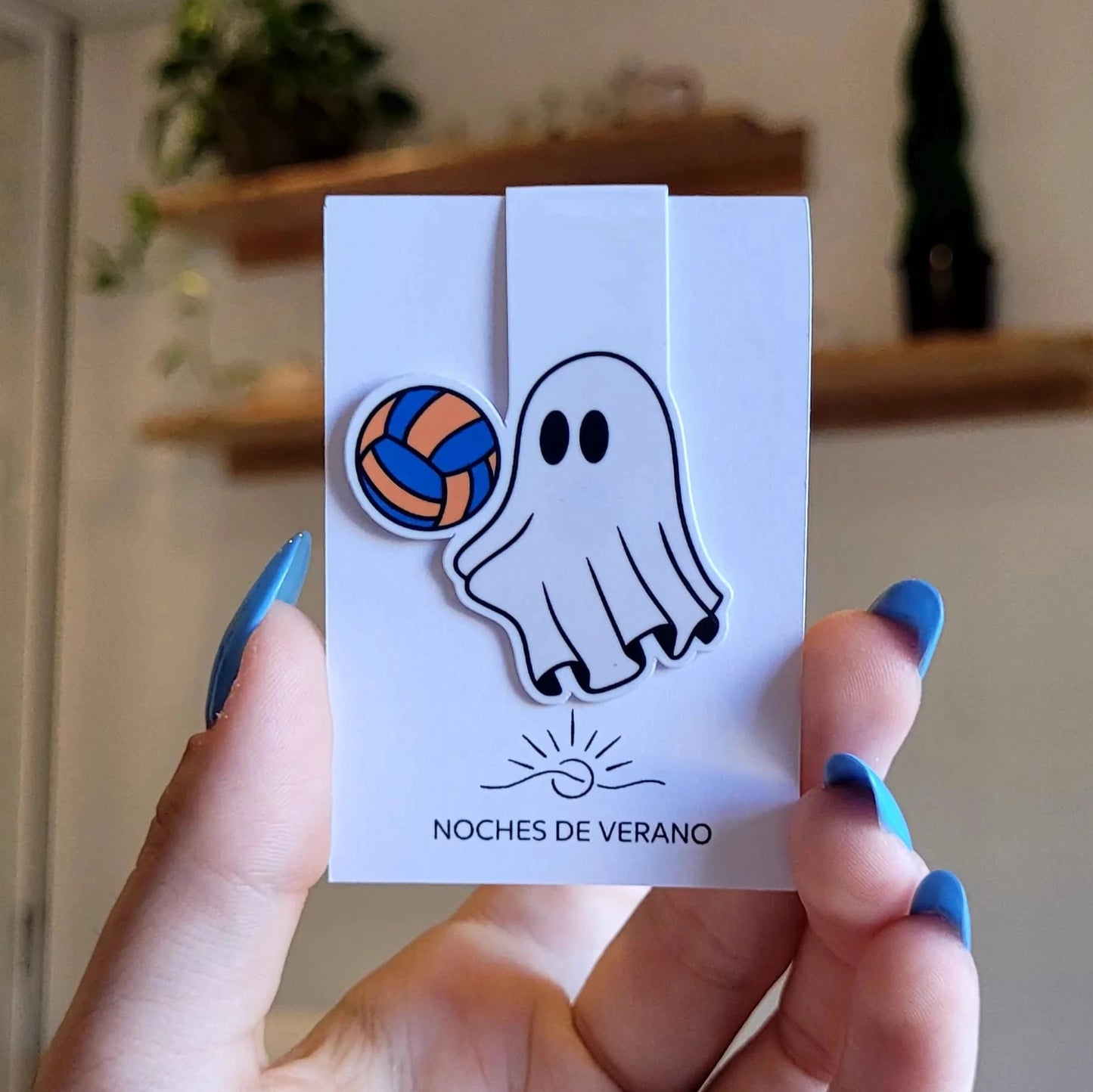 Marcapáginas magnético con diseño divertido de fantasma jugando al voleibol con un balón azul y amarillo, perfecto para lectores que busquen un marcador de libros único y original de deportes.